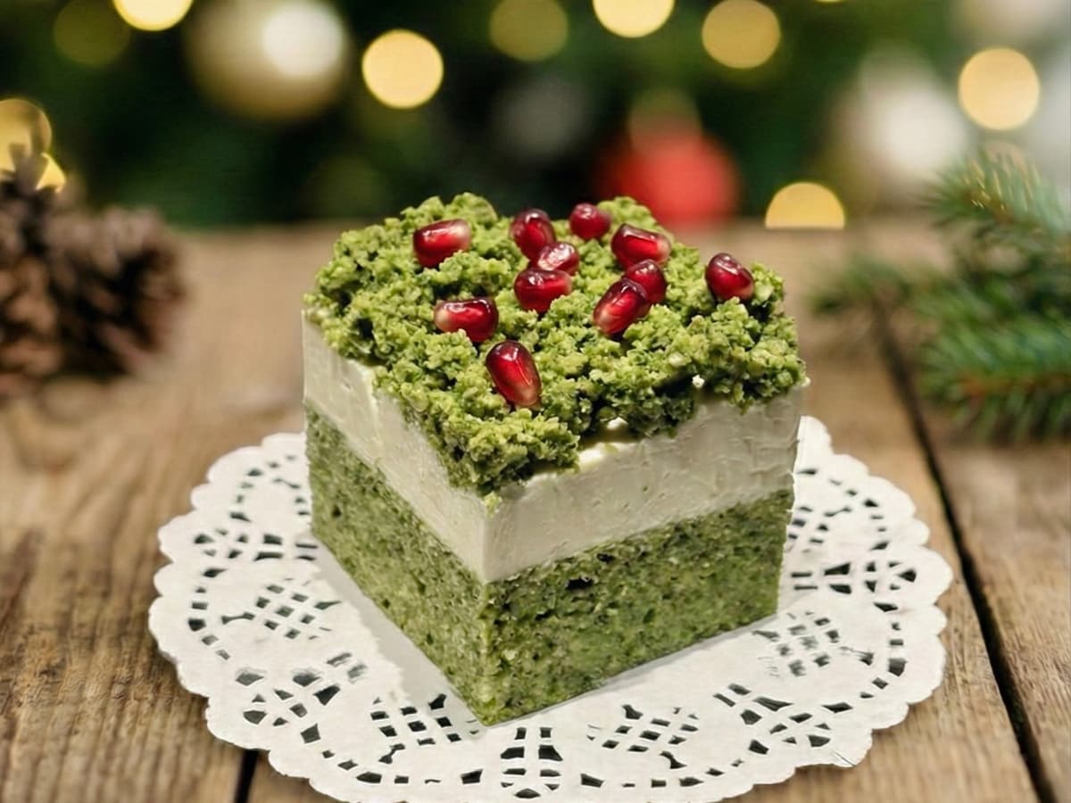 Eleganckie zielone ciasto pistacjowe z granatem i jadalnymi kwiatami na świątecznym stole